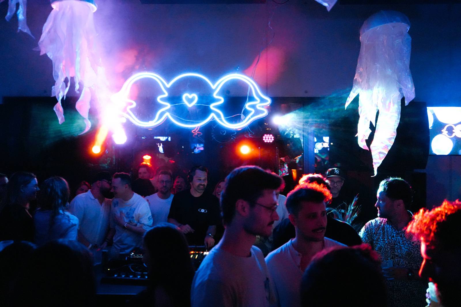 DJ playing under the neon LAGOOON logo at a LAGOOON party