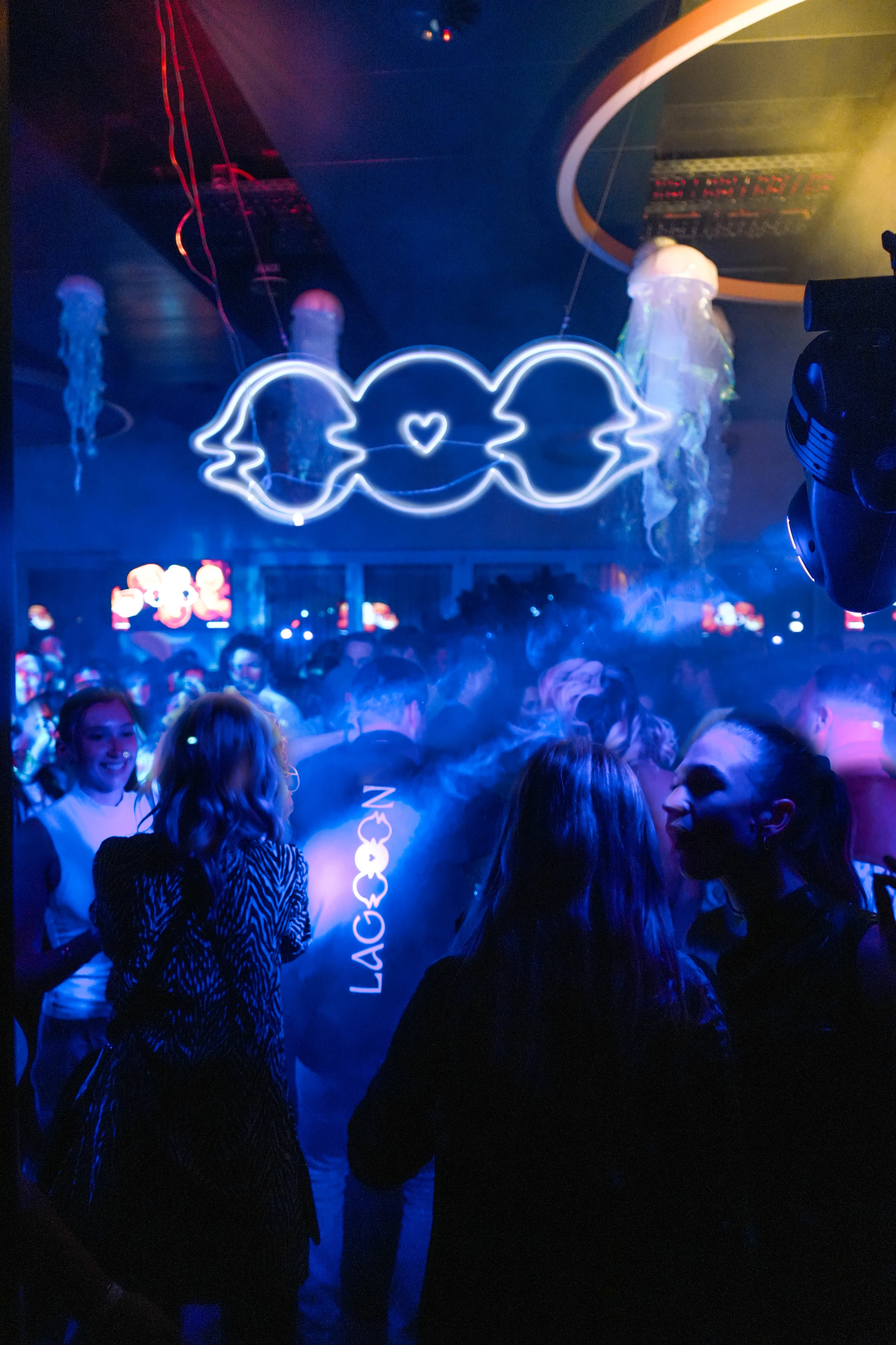 Crowd dancing under the neon LAGOOON logo and glowing jellyfish